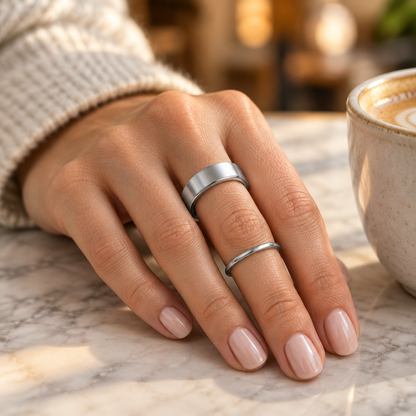 Silver Uhoofit R10 smart ring worn on a woman's hand beside a plain silver band